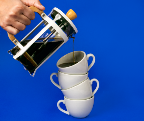 prensa francesa y tazas de café sobre fondo azul 